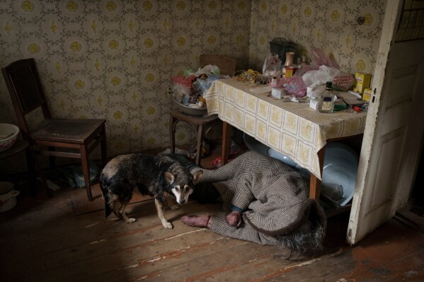 A dog stands next to the body of an elderly woman killed inside a home in Bucha on the outskirts of Kyiv, Ukraine, Tuesday, April 5, 2022. (AP Photo/Felipe Dana, File)