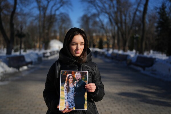 Liliia, 30, holds a photograph of her with her boyfriend Bohdan, now a prisoner of war, as she poses for a portrait in Kyiv, Ukraine, Saturday, Feb. 21, 2026. (AP Photo/Sergei Grits)