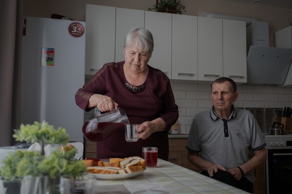 Liudmyla Shytik, 77, pours a drink for her husband Viktor, 78, in their social housing apartment in the Kyiv region of Ukraine, Wednesday, Feb. 18, 2026. (AP Photo/Efrem Lukatsky)