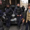 Pedro Elias Garzon Delvaux, right, walks past as police officers block an entrance to the Louvre after thieves carried out a daylight raid on French crown jewels, in Paris, Oct. 19, 2025.