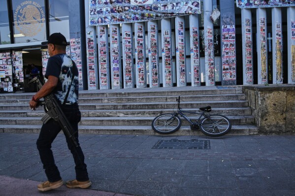 A police officer walks past posters bearing the faces of missing persons in front of the Special Prosecutor's Office for Missing Persons in Guadalajara, Mexico. Wednesday, Feb. 25, 2026. (AP Photo/Marco Ugarte)