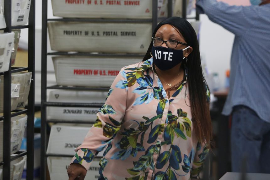 A worker of Miami-Dade County Elections Department walks past US Postal Service baskets with mail-in ballots during the primary election amid the coronavirus disease (Covid-19) outbreak in Miami, Florida, on August 18, 2020.