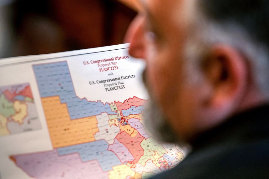 Republican state Rep. Matt Morgan holds a map of the new proposed congressional districts in Texas, during a legislative session on August 20, 2025.