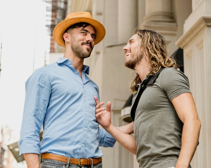 Two men smiling and chatting outdoors, capturing a moment of peaceful bliss and carefree conversation.