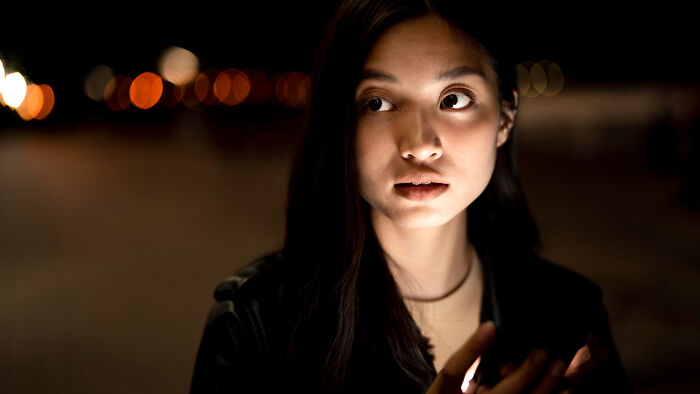 Young woman looking worried at night with blurred city lights, representing common worries women face daily.