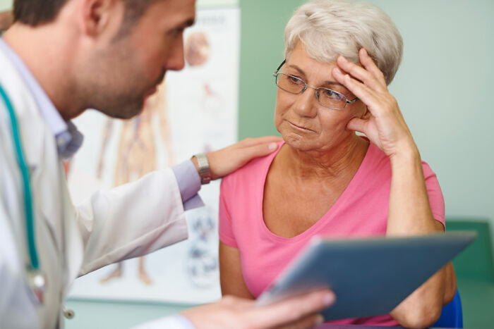 Doctor comforting worried senior woman during a medical consultation about common things women worry about daily.