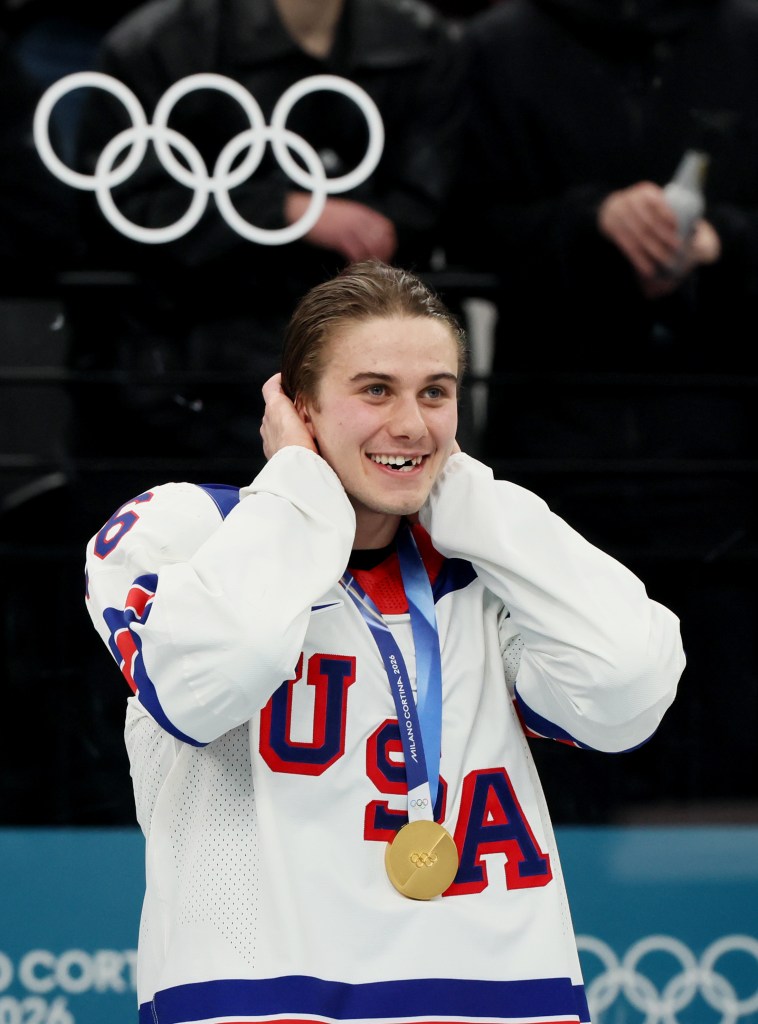 An American ice hockey player wearing a gold medal with the Olympic rings.