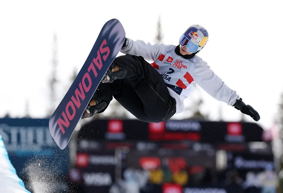 Snowboarder performs high-flying trick on a halfpipe, displaying athletic skill and balance during a winter sports competition