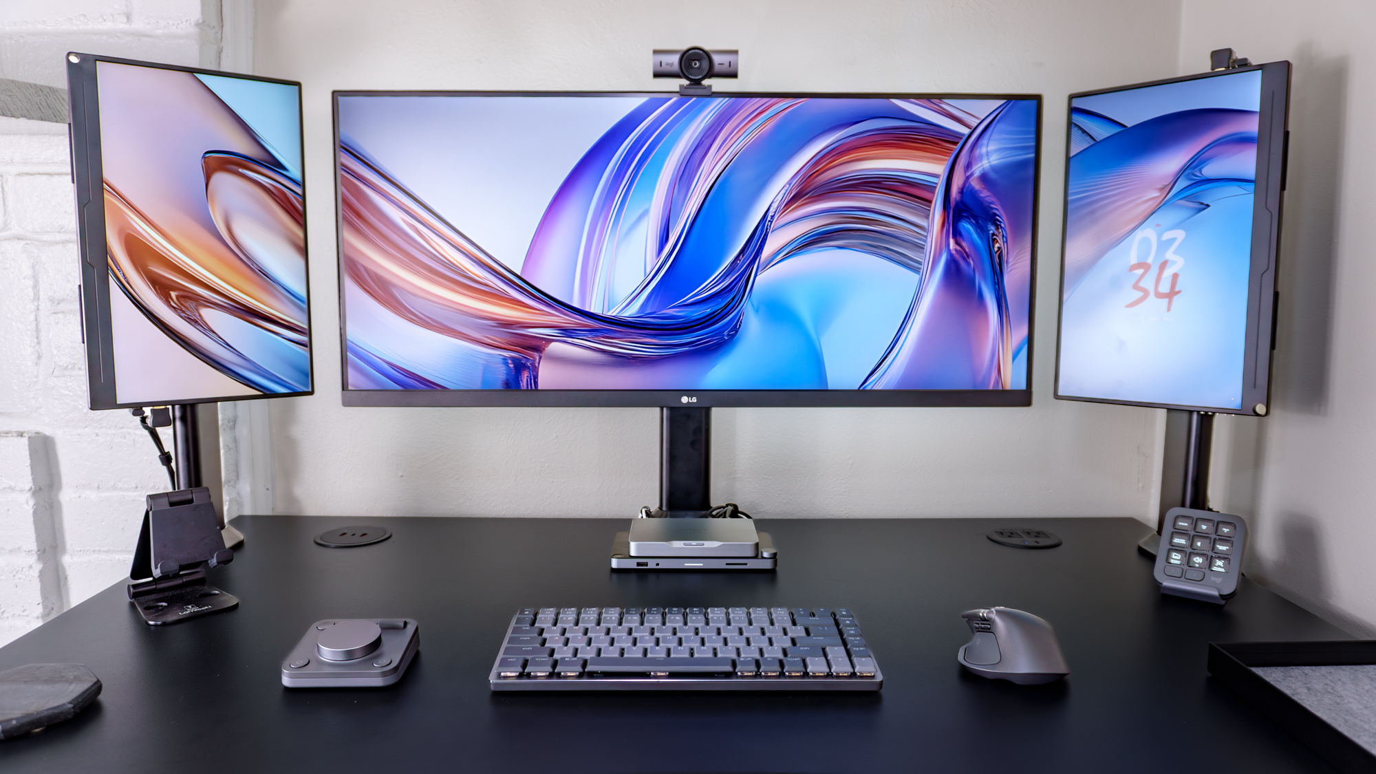 A triple monitor setup powered by the Khadas Mind 2S outfitted entirely with peripherals from Logitech's MX Master Series