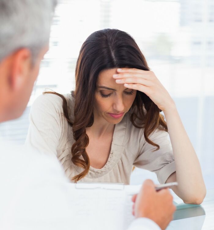 Woman with worried expression holding her forehead during a discussion, illustrating things women worry about daily.