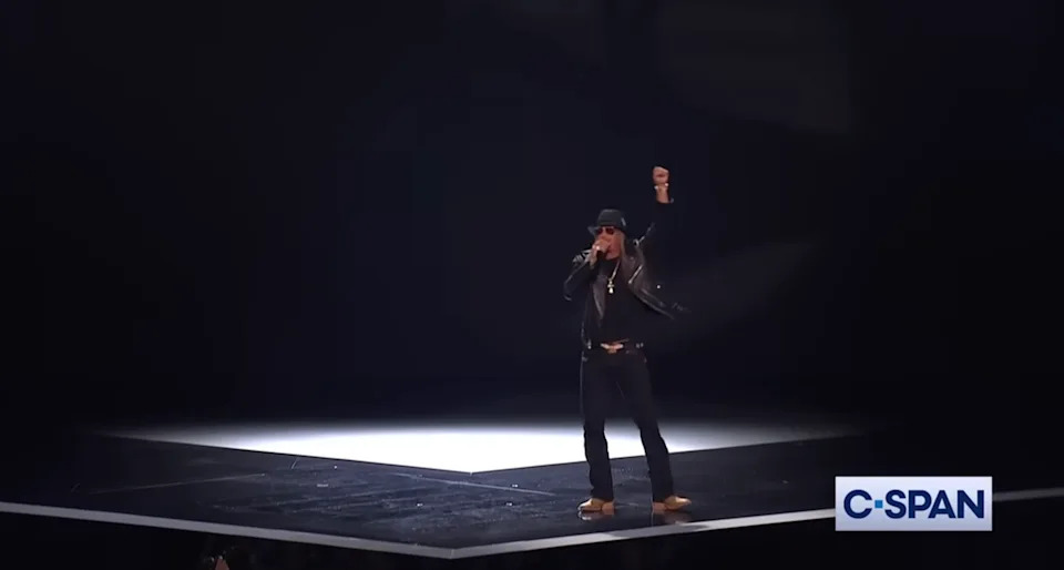 A performer on stage raises a fist, wearing a hat and leather jacket, during a televised event. C-SPAN logo visible in the corner