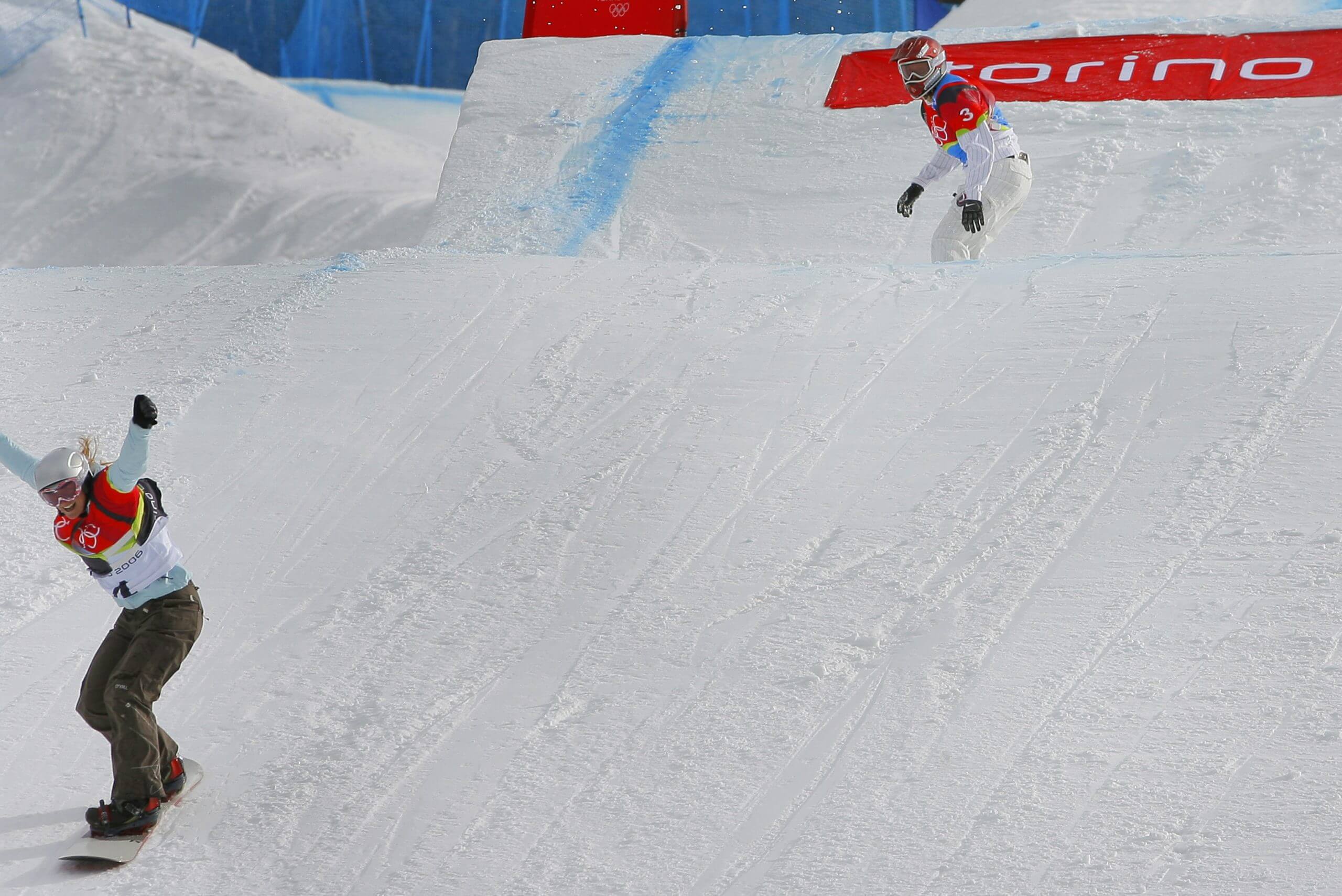 Two snowboarders cross the finish line