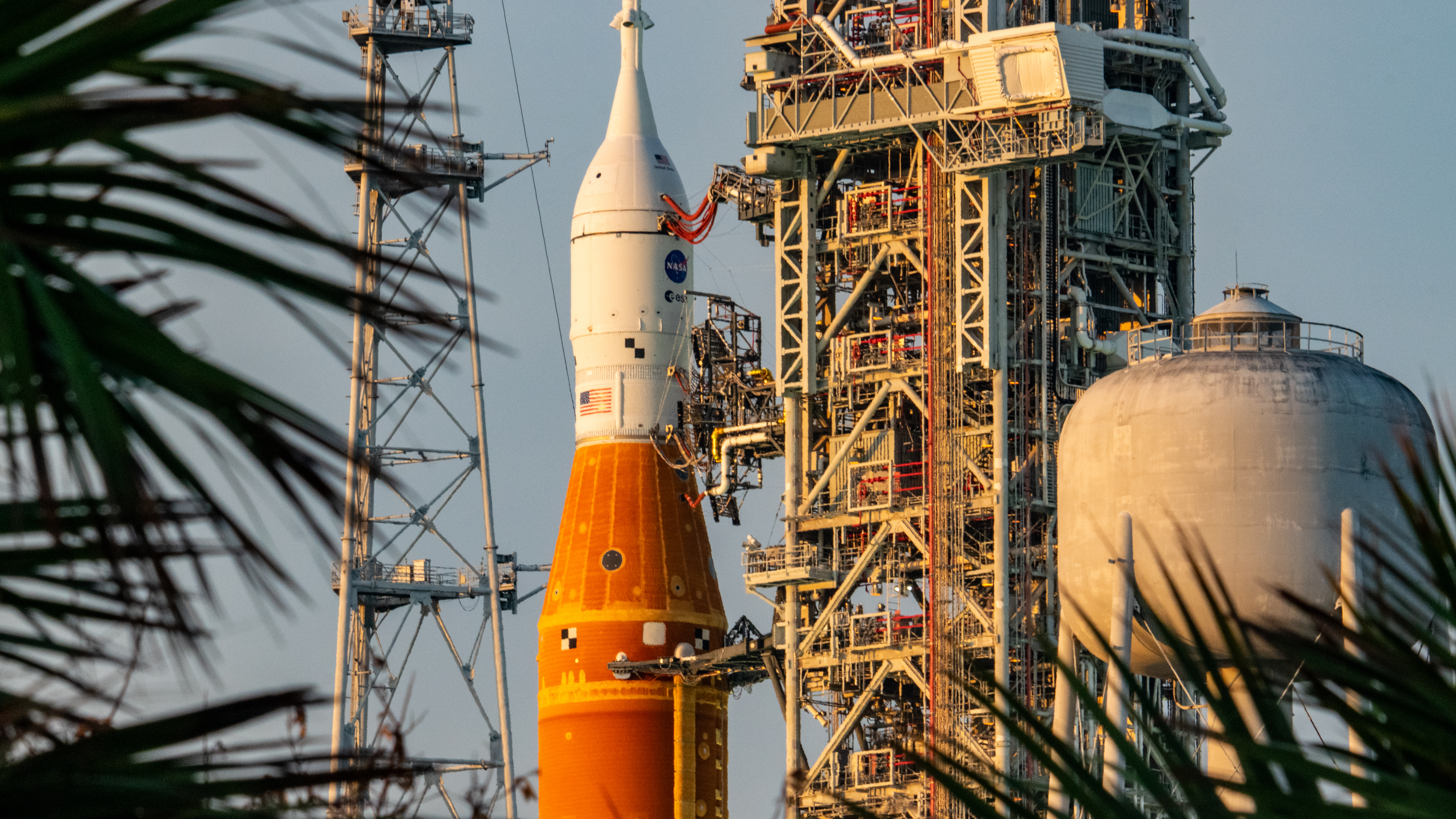 An orange rocket with a white top stands against a dynamic sky.