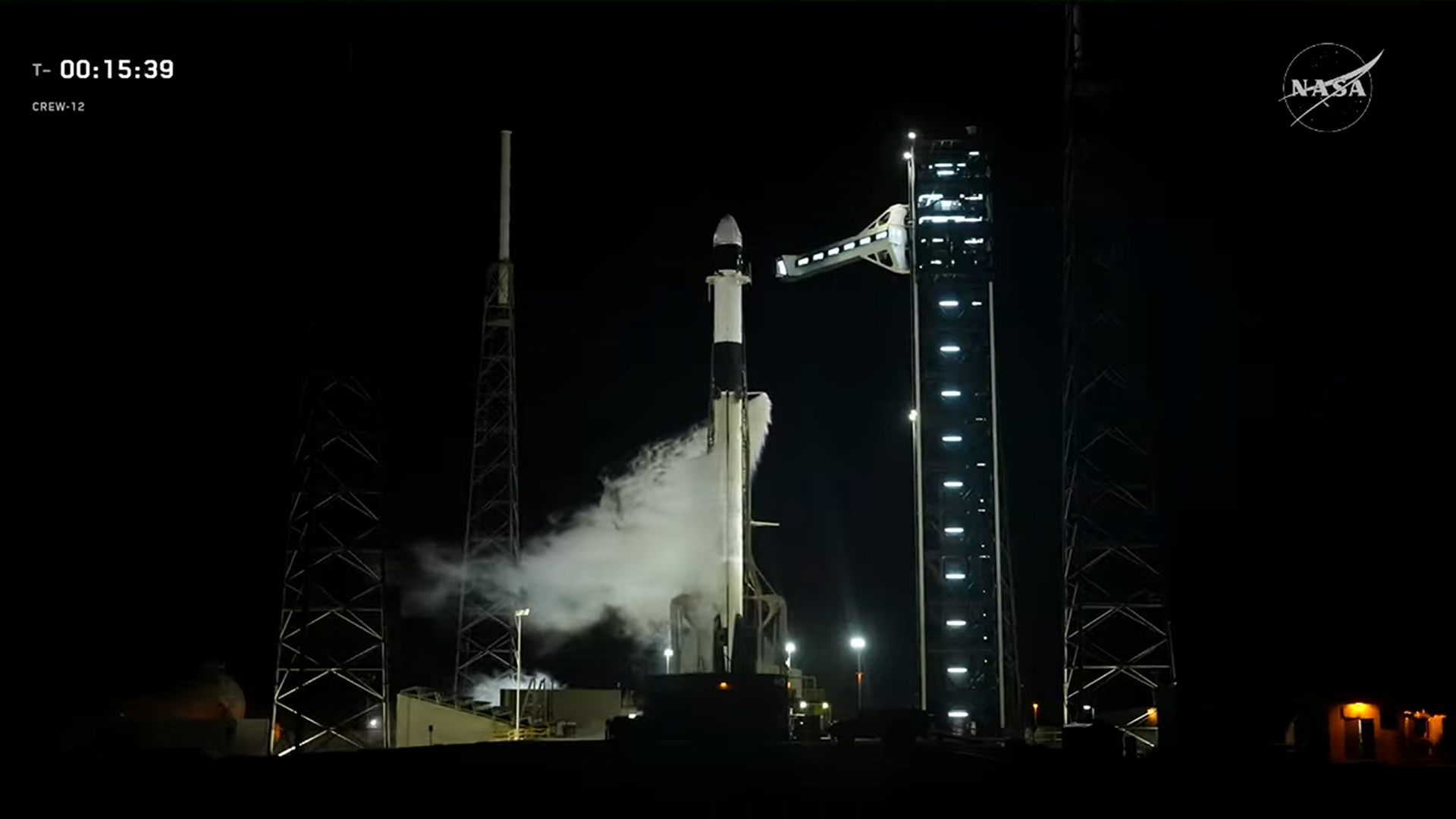 A black and white SpaceX rocket on the launch pad for Crew-12