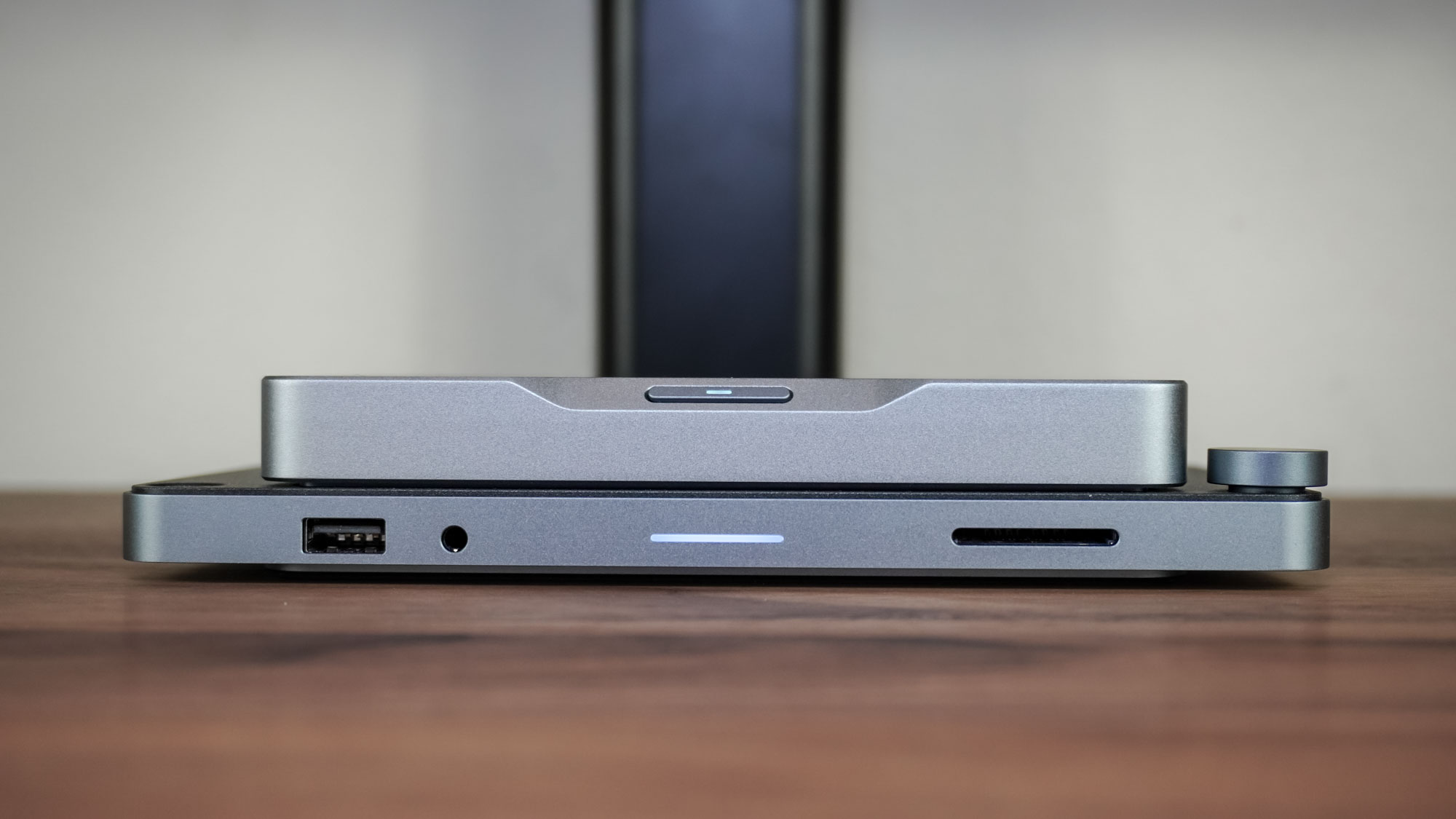 The Khadas Mind 2S mini PC attached to the Mind Dock on a desk with a monitor stand in the background