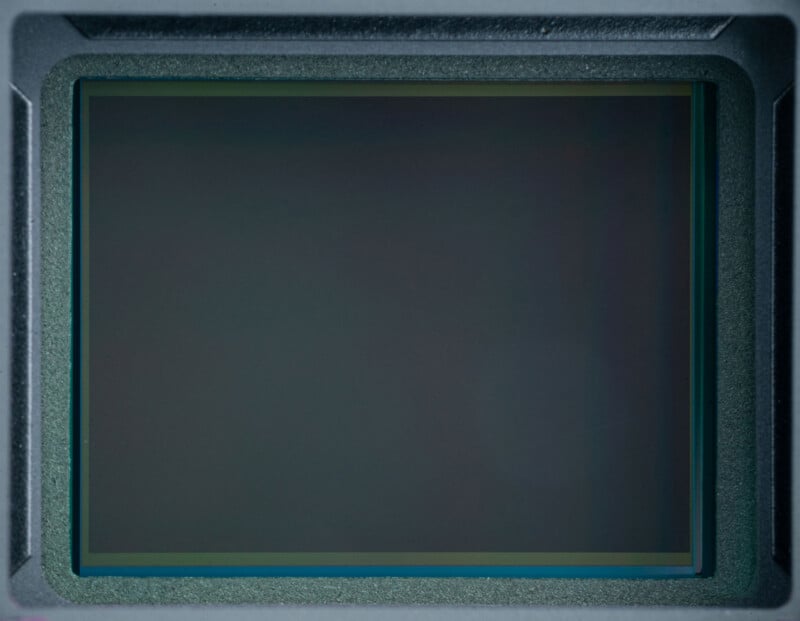 Close-up view of a digital camera image sensor, showing a rectangular, reflective surface with a thin border, set within a dark, textured frame.