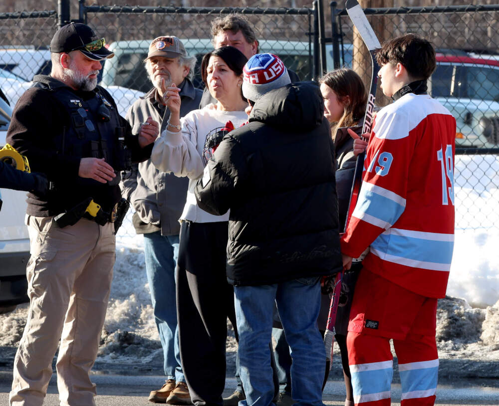 Hockey parents and a player speak to a police officer outside of the Lynch Arena in Pawtucket, R.I., after a shooting at the ice rink on Feb. 16. (Mark Stockwell/AP)