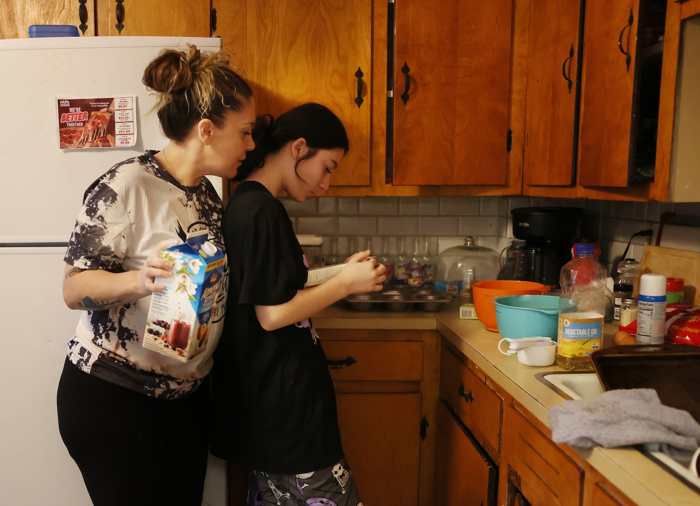 Massarone leaned over her daughter, Sophia, 14, as she read the instructions for a box of brownies that they will bake together.