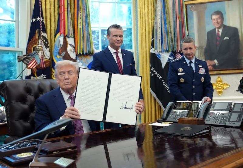 President Donald Trump displays a signed executive order renaming the Department of Defense as the Department of War as U.S. Defense Secretary Pete Hegseth (C) and Chairman of the Joint Chiefs of Staff Air Force Gen. Dan Caine (R) look on during a press availability in the Oval Office of the White House on September 05, 2025 in Washington, DC.