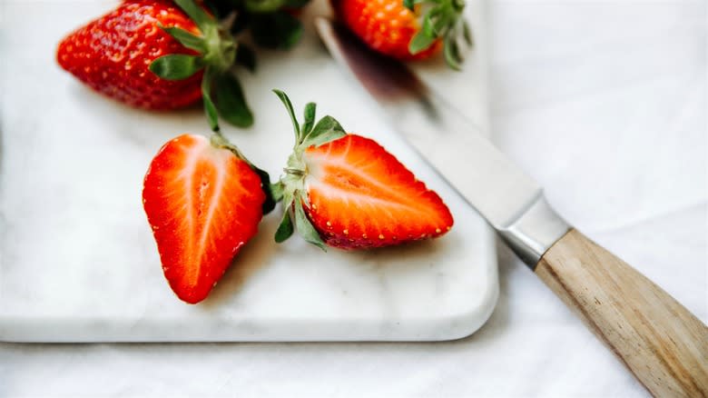 A bright red sliced strawberry on a cutting board