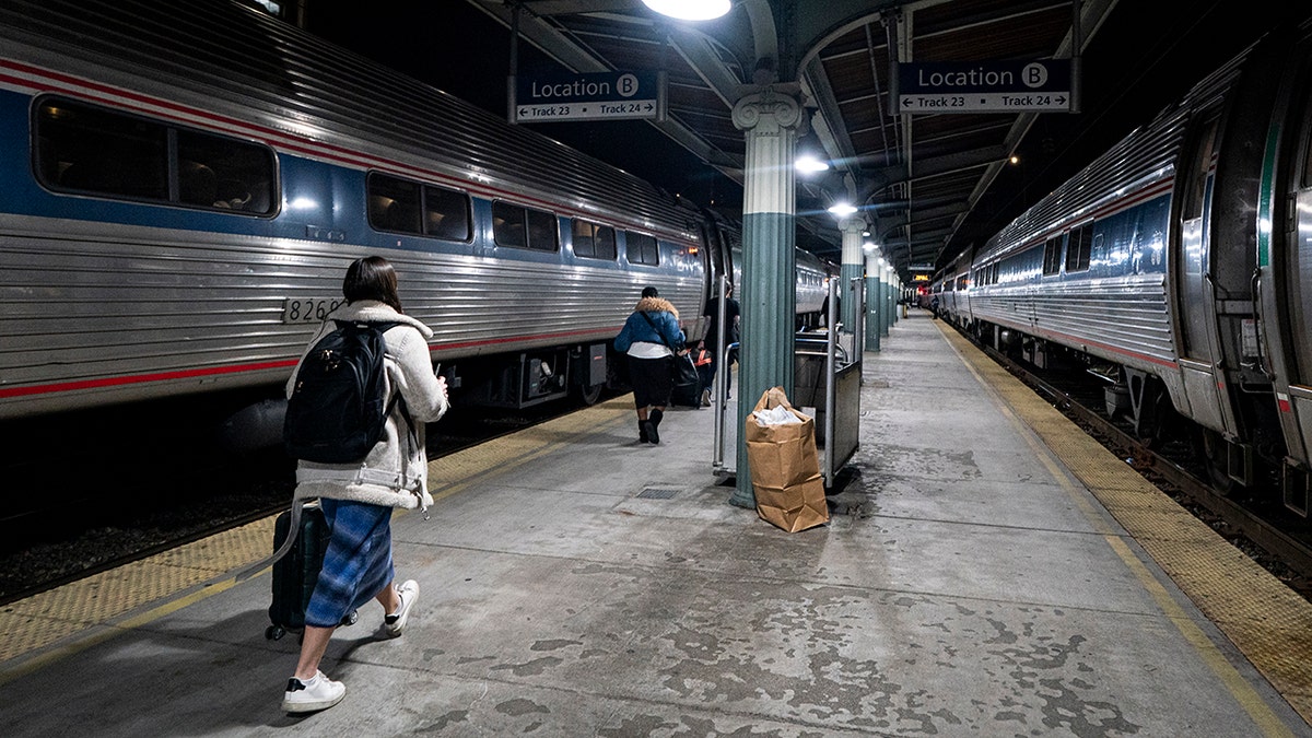Travelers walk on platform to board a Northeast Regional Amtrak train bound for New York, at Union Station, on night of January 13, 2026 in Washington, DC.