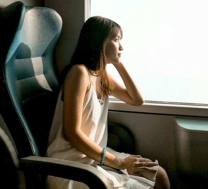 Woman sitting by a window, looking thoughtful and worried, illustrating common things women worry about daily.