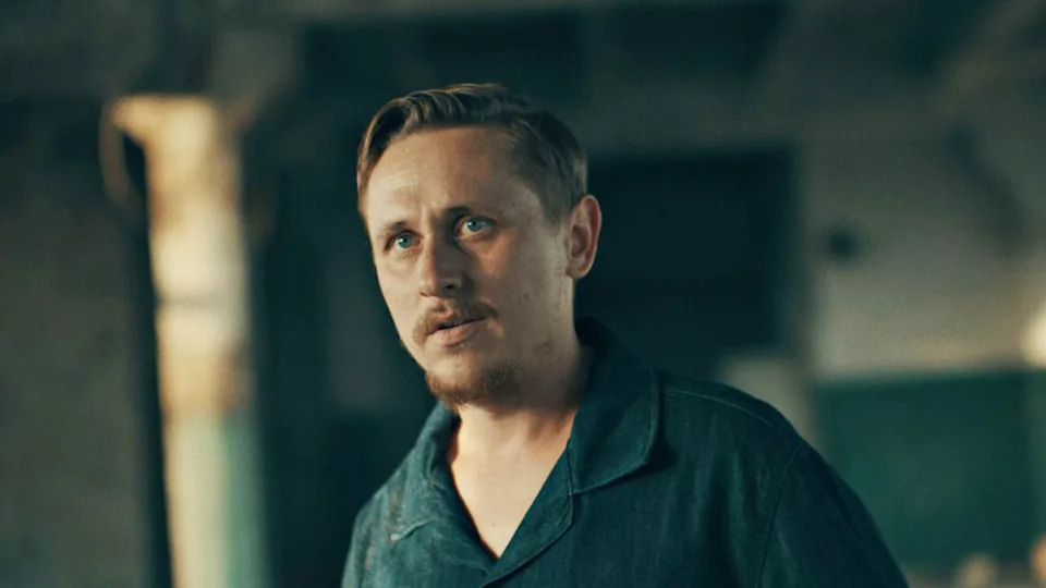 Dima, wearing a blue collared t-shirt, speaks to the BBC in an undisclosed warehouse.