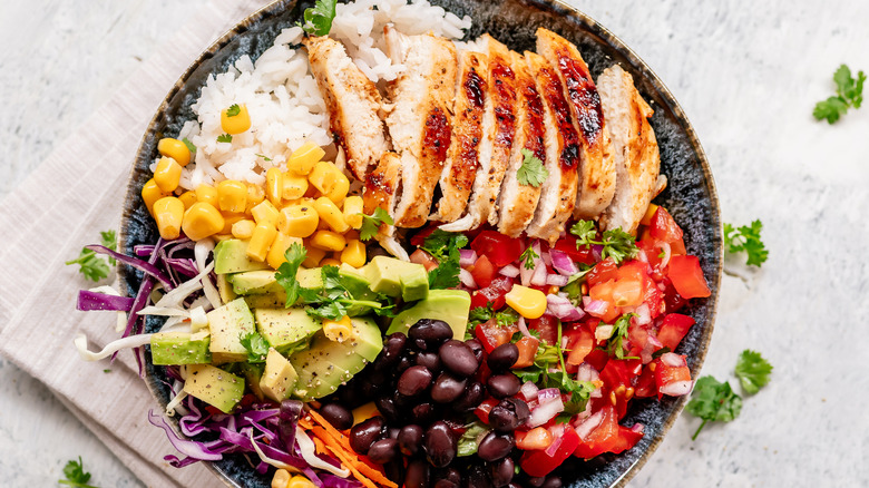 Burrito bowl with grilled chicken, rice, corn, black beans, pico de gallo, shredded cabbage and carrot, and avocado chunks