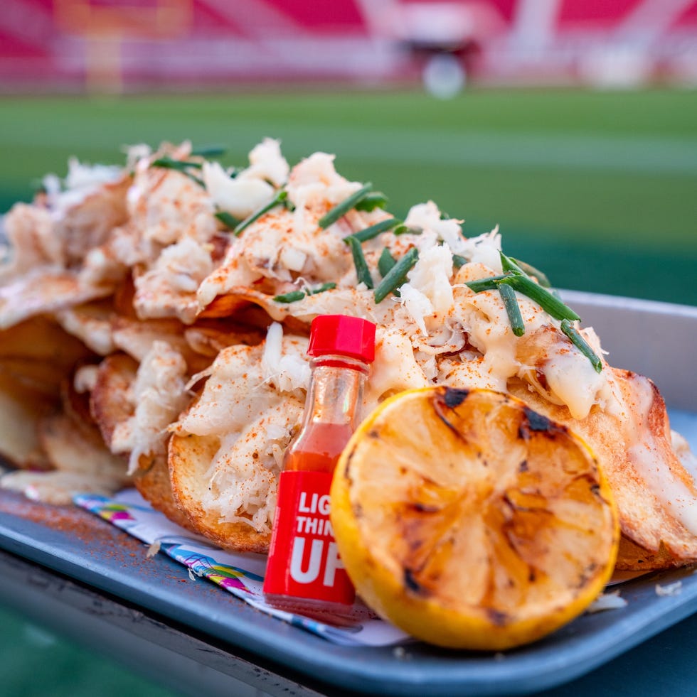 loaded nachos with toppings and a sauce bottle on a tray