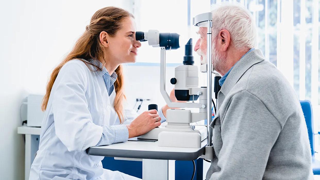 Female optometrist examining an older man’s eyes