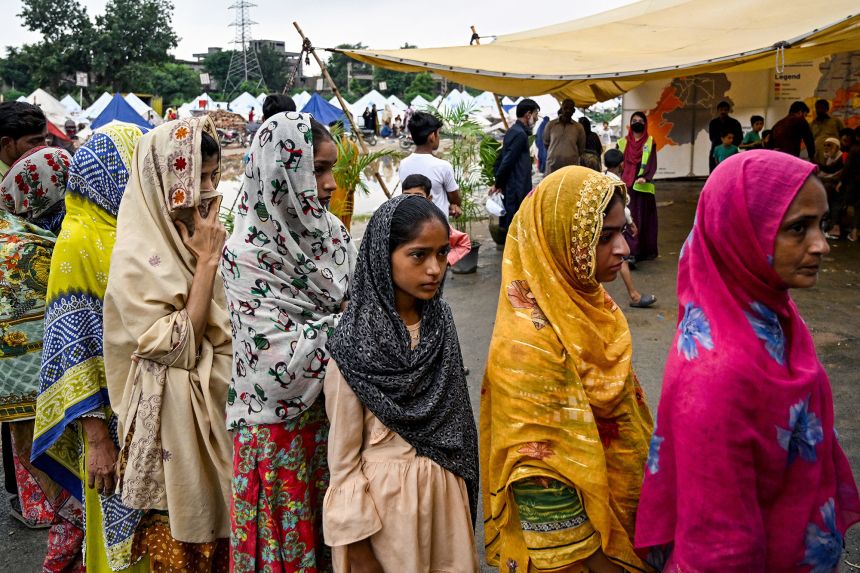 Women and girls queue near a mobile health unit at a flood relief camp in Punjab province, on August 31. Climate crisis-induced flash floods in Pakistan have exacerbated period poverty.