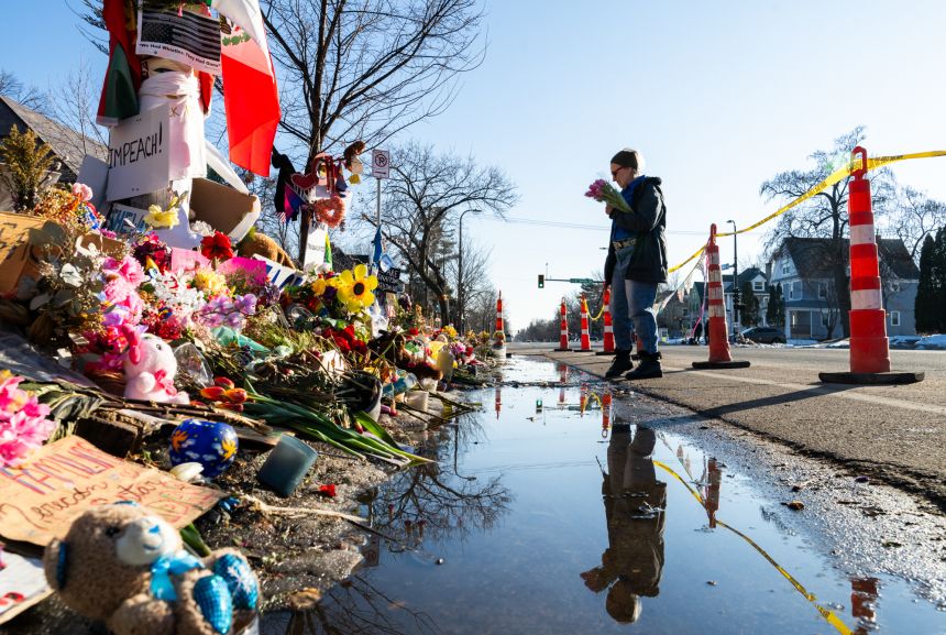 A woman carries flowers on February 12, 2026, at a memorial for Renee Nicole Good who was shot and killed by an ICE agent in Minneapolis.
