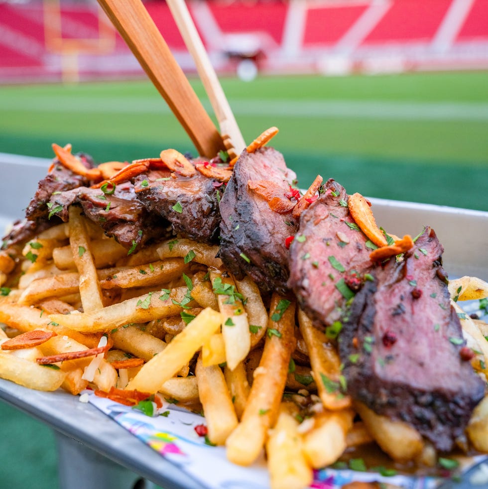 beef brisket served on top of french fries in a stadium setting