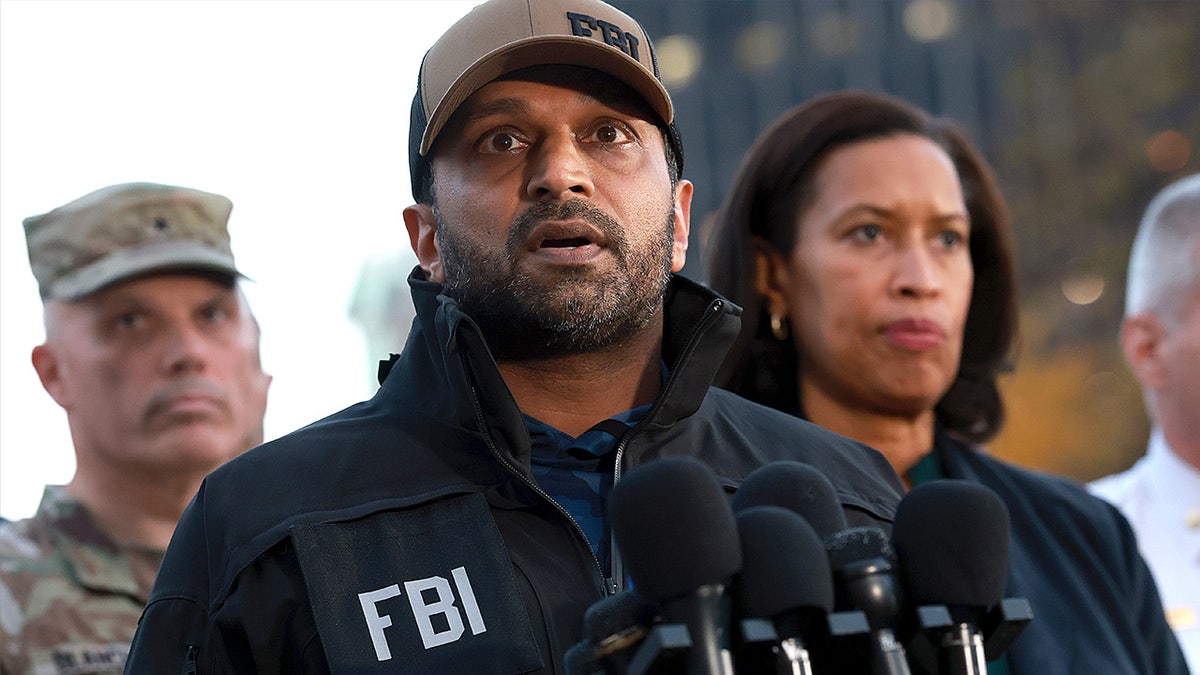 Kash Patel speaks to reporters while standing beside Muriel Bowser during a media briefing.