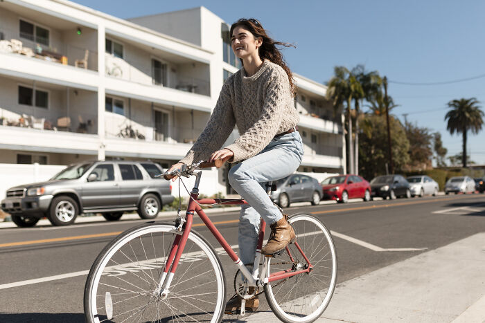 Young woman smiling while riding a bike outdoors, representing recovery and resilience from PTSD after a coma experience.