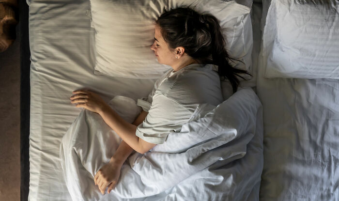 Young woman lying in bed resting, illustrating the experience of people who’ve been in a coma and PTSD effects.