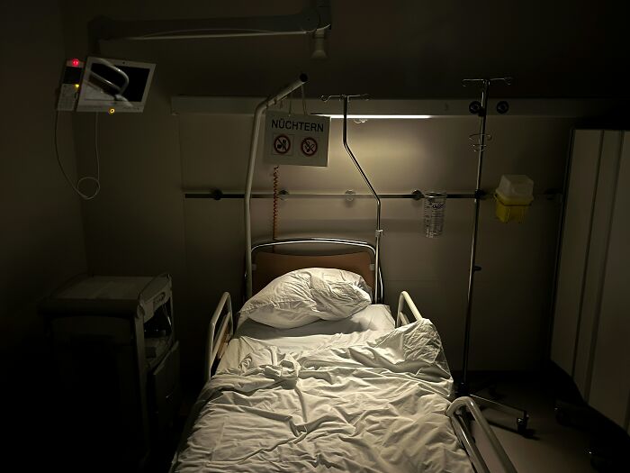 Dimly lit empty hospital bed with medical equipment, illustrating the experience of people who’ve been in a coma.
