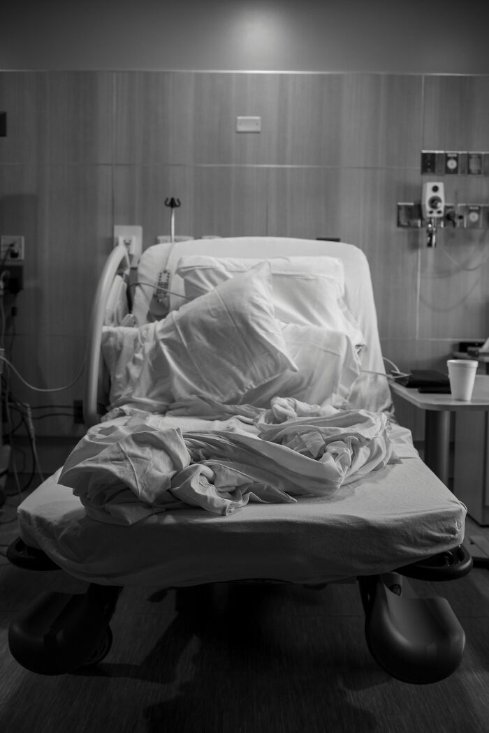 Hospital bed with disheveled sheets and pillows in dimly lit room, representing experiences of people in a coma with PTSD.