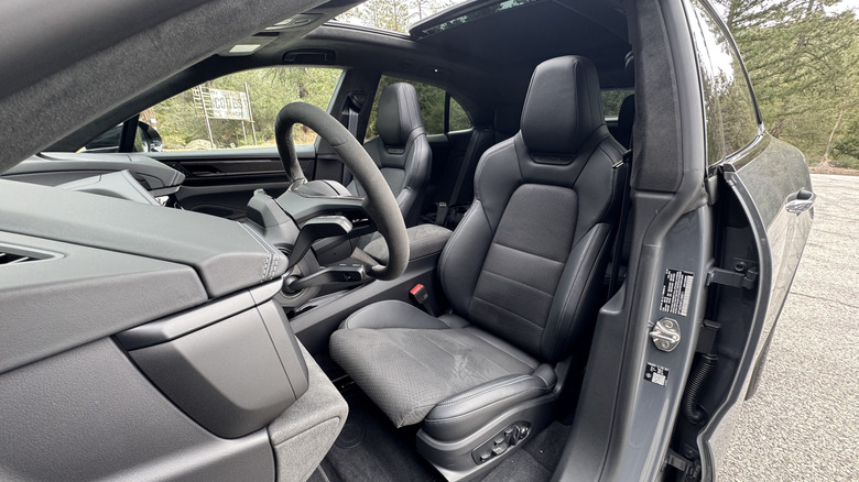 A look through the driver's door at the driver's seat with trees visible in the background
