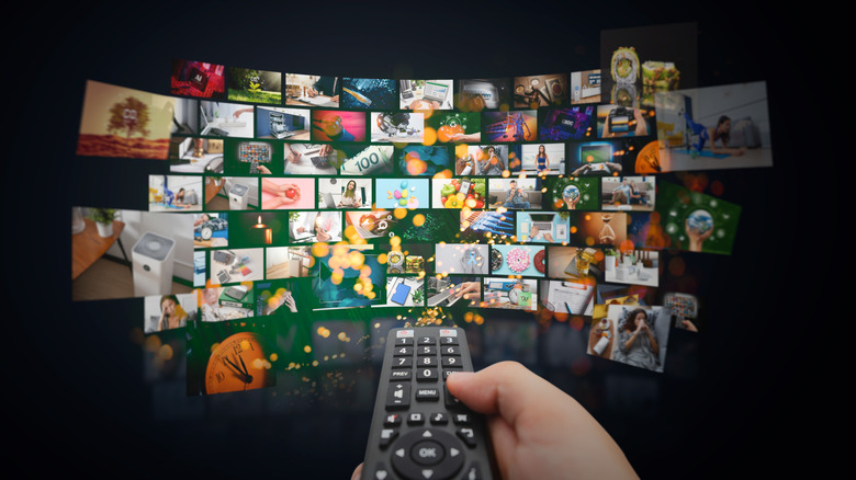 Several video thumbnails grouped up forming a screen, with a person holding a remote pointing to them.