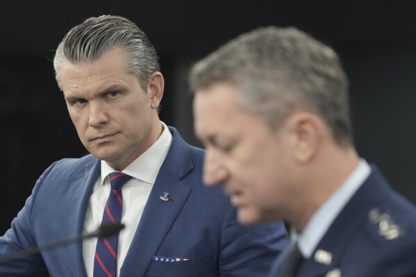 Defense Secretary Pete Hegseth listens to Chairman of the Joint Chiefs of Staff Gen. Dan Caine, during a press briefing at the Pentagon, Monday, March 2, 2026, in Washington. (AP Photo/Mark Schiefelbein)