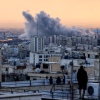 A person standing on the roof of a building looks at a plume of smoke rising after a strike on the Iranian capital, Tehran, on Tuesday.