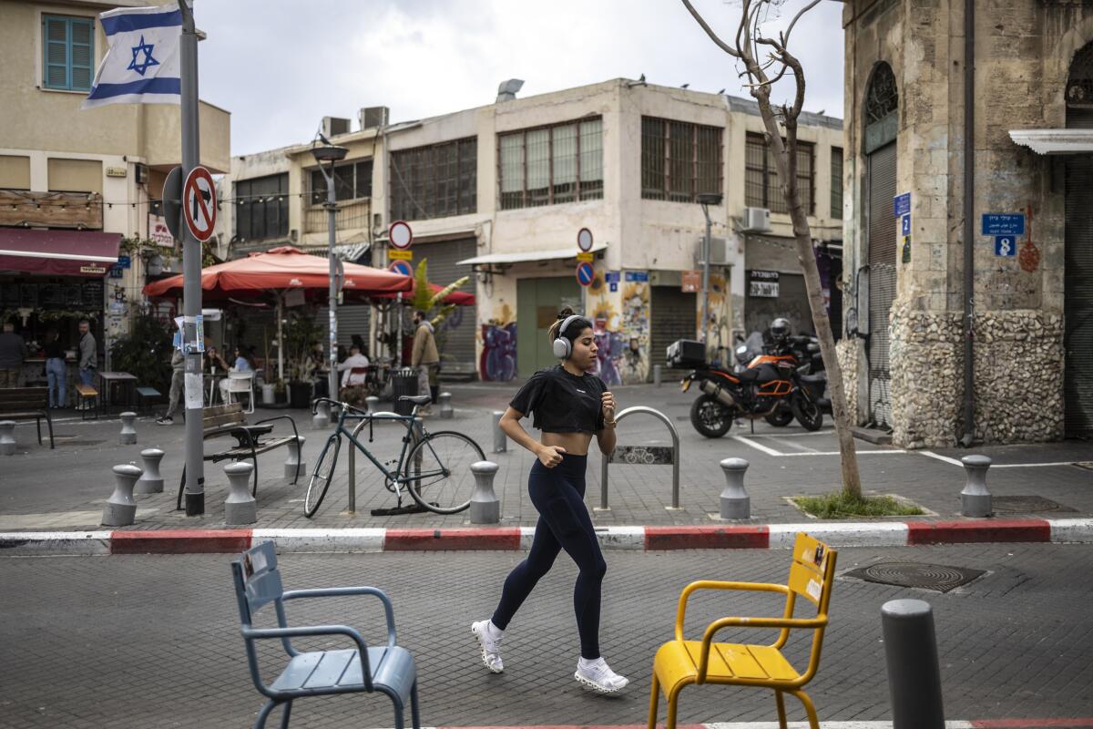 A woman jogs along a street amid closed shops