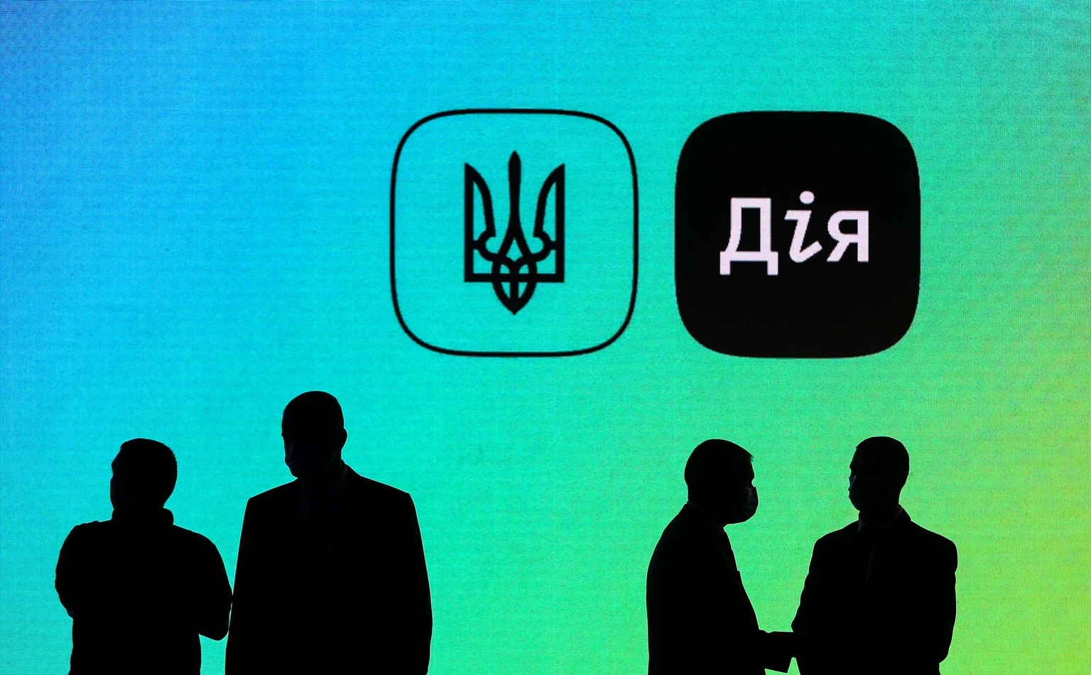 Silhouettes of people stand in front of a screen displaying the logo of the Diia app during the Diia Summit in Kyiv, Ukraine, on Oct. 5, 2020. 