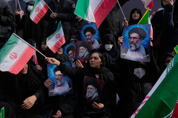 People wave Iranian flags as they hold posters of the late Supreme Leader Ayatollah Ali Khamenei, showing him at different ages, during a rally to support his son Ayatollah Mojtaba Khamenei, who succeeds his father as the new supreme leader, in Tehran, Iran, Monday, March 9, 2026. (AP Photo/Vahid Salemi)