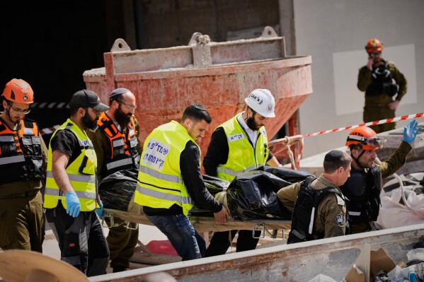 Israeli security forces and ZAKA rescue service members carry the body of a man killed in an Iranian missile strike in Yehud, Israel, Monday, March 9, 2026. (AP Photo/Ohad Zwigenberg)