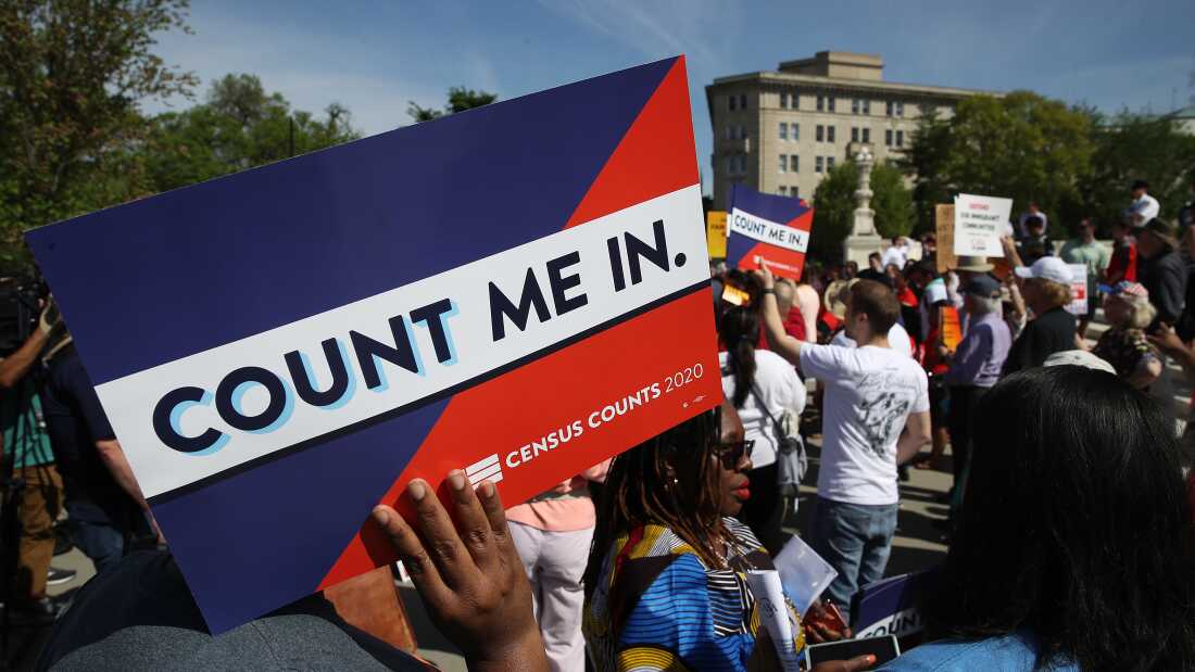Protesters hold signs saying “COUNT ME IN” at a 2019 rally against the Trump administration’s push for a census citizenship question outside the U.S. Supreme Court in Washington, D.C.