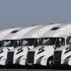 A line of white semi-trucks parked side by side. 