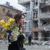 A woman carrying a bouquet of yellow and white flowers walks past a high-rise residential building heavily damaged by a Russian drone strike in the Shevchenkivskyi district of Kyiv, Ukraine, on May 25, 2025.