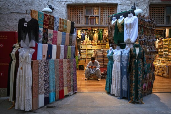 A vendor sits inside a shop at the empty Al Seef market, next to the historic Al Fahidi neighborhood along Dubai Creek, one of the main tourist areas of Dubai, United Arab Emirates, Friday, March 13, 2026, as tourism slows amid regional tensions linked to the Iran war. (AP Photo/Fatima Shbair)